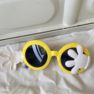 Close-up of yellow cartoon sunglasses featuring white glove icons and round black lenses