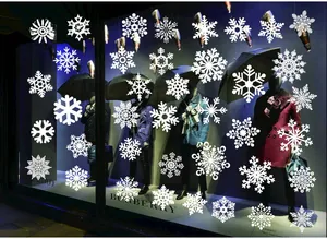 Detailed view of various white snowflake window clings on a glass display for Christmas