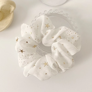 White chiffon scrunchie with gold foil stars and polka dots displayed on a tray