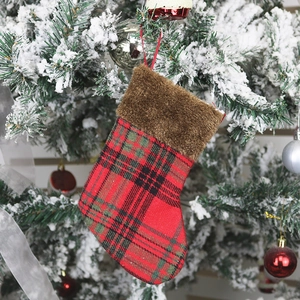 Classic red plaid Christmas stocking with brown faux fur trim hanging on a snowy tree