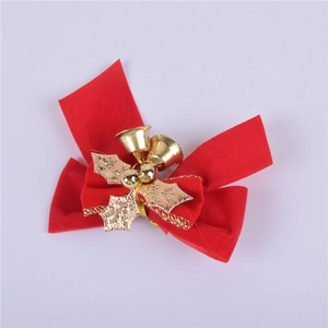 Close-up of red velvet Christmas bow with gold metal holly leaves and small golden bells