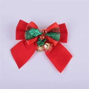 Close-up of red velvet Christmas bow with gold bells and green holly leaf details