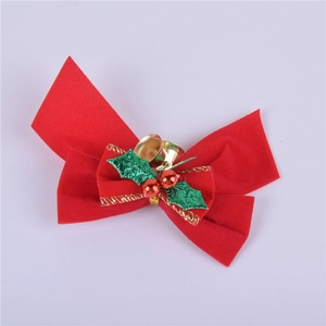 Detail of a red velvet Christmas bow featuring golden bells and green holly leaf accents