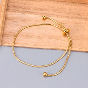 Detail of gold snake chain bracelet featuring adjustable slider bead and polished beads