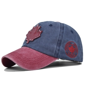 Detail of red maple leaf embroidery on a washed navy and burgundy cotton baseball cap