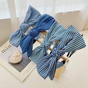 Detail view of four blue denim bow headbands displayed on a wooden stand