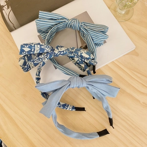 Detailed top view of three knotted fabric headbands in striped, floral, and solid denim blue