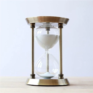 Close-up of vintage bronze metal hourglass timer with fine white sand and brushed finish