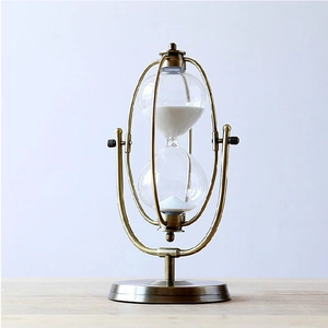 Detail of vintage bronze metal rotating hourglass with fine white sand and 360-degree stand