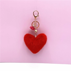 Detailed view of red plush heart keychain with pink tassel and gold metal ring