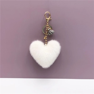 Close-up of white plush heart keychain with grey tassel and golden metal hardware