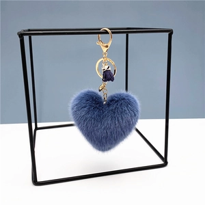 Blue plush heart keychain with gold tassel hanging in a modern geometric frame