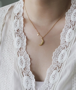 Detail of 18K gold plated celestial necklace with moon and star pendants on a model