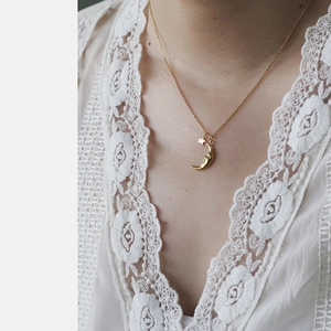 Close-up of 18K gold plated moon and star pendant necklace on a delicate chain
