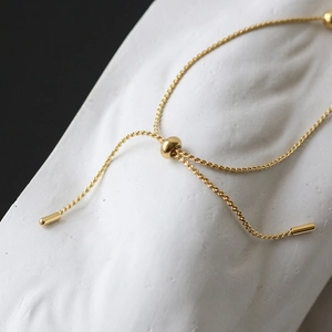 Detail of adjustable gold-plated titanium slider buckle on heart charm bracelet