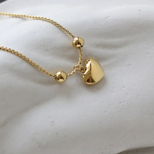 Close-up of 18K gold-plated heart pendant and beads on a twisted chain necklace