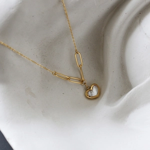 Close-up of heart-shaped shell necklace with gold titanium steel paperclip chain detail
