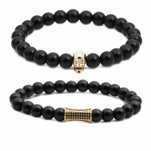Men's beaded bracelets with gold skull and rhinestone cylinder charms on white background