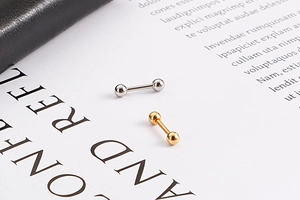 Gros plan de boucles d'oreilles boules dorées et argentées sur un fond de livre épuré