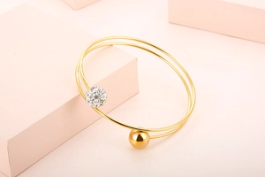 Detail of gold double-layered bangle with a polished bead and a crystal-paved sphere