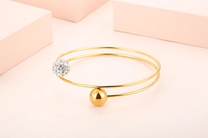 Detail of gold double-layer bangle featuring one rhinestone sphere and one smooth gold ball