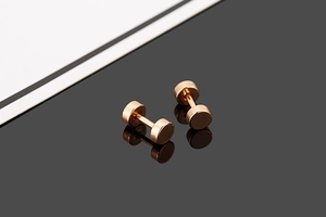 Macro detail of rose gold disc stud earrings with mirror polished finish and reflection