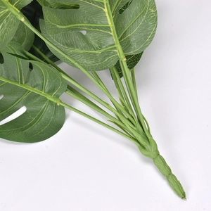 Realistic green artificial monstera leaves with detailed stems on white background