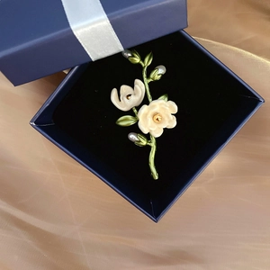 Detailed close-up of a floral camellia brooch with freshwater pearl in a gift box