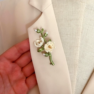 Vintage enamel camellia flower brooch with baroque freshwater pearls on a beige blazer lapel