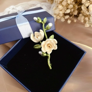 Detailed view of enamel camellia brooch with freshwater pearls in a gift box