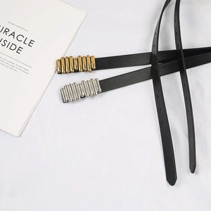 Detail of slim women's black leather belts with textured gold and silver metal buckles