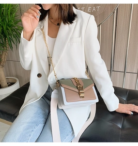Detail of color-block crossbody bag featuring green, brown, white panels and gold hardware