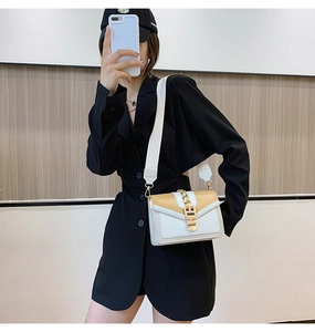 Detail view of khaki and white crossbody bag with wide shoulder strap and gold chain link