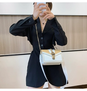 Detail view of beige and white crossbody bag with metal chain and wide shoulder strap