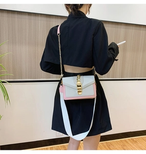Fashionable crossbody square bag with pink contrast shown on a model in a modern interior