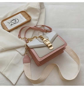 Detail of pink and beige PU leather crossbody bag with gold lock and wide shoulder strap