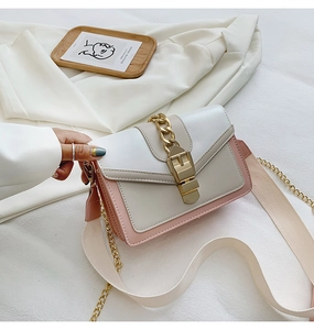 Detail of color-block crossbody bag with gold metal buckle and wide woven shoulder strap