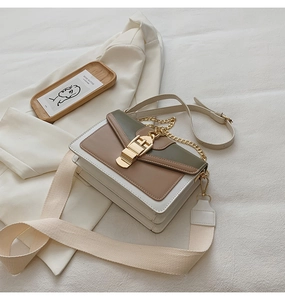 Detail of cream crossbody bag featuring green accents and gold hardware with wide strap