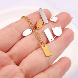 Polished stainless steel pendants and gold chains held in hand for DIY jewelry making