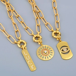 Close-up of three gold thick chain necklaces with Luck charm and rhinestone pendants
