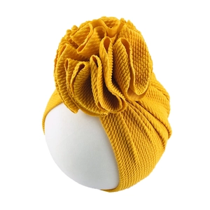Detail of mustard yellow waffle knit baby turban hat with large 3D flower decoration