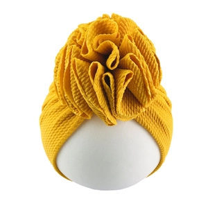 Detailed view of ginger baby turban hat with large flower and textured fabric on model
