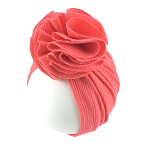 Detail of baby turban hat featuring coral pink waffle knit fabric and 3D flower