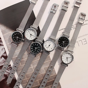 Detail view of silver mesh strap watches with white and black dials on a magazine