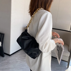 Fashionable black soft cloud bag with a chunky gold chain strap shown on a model's shoulder