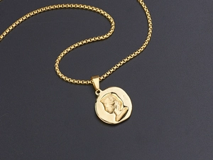 Detail of a vintage gold titanium necklace with a relief coin pendant on a black background