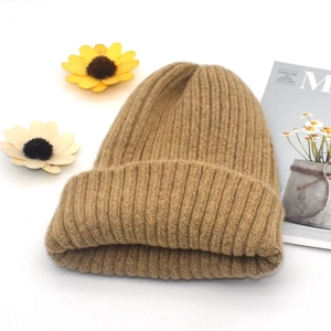 Chunky knit camel beanie with wide ribbed cuff shown on white background with sunflowers