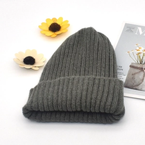 Detail of dark grey chunky knit beanie on white background with decorative floral accents
