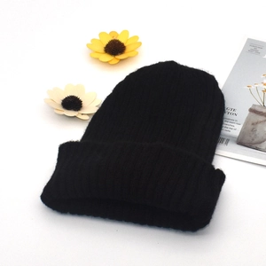Close-up of black ribbed knit beanie with cuffed edge on white decorative background