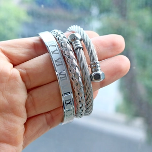 Detailed view of three-piece silver stainless steel roman numeral and braided bracelets